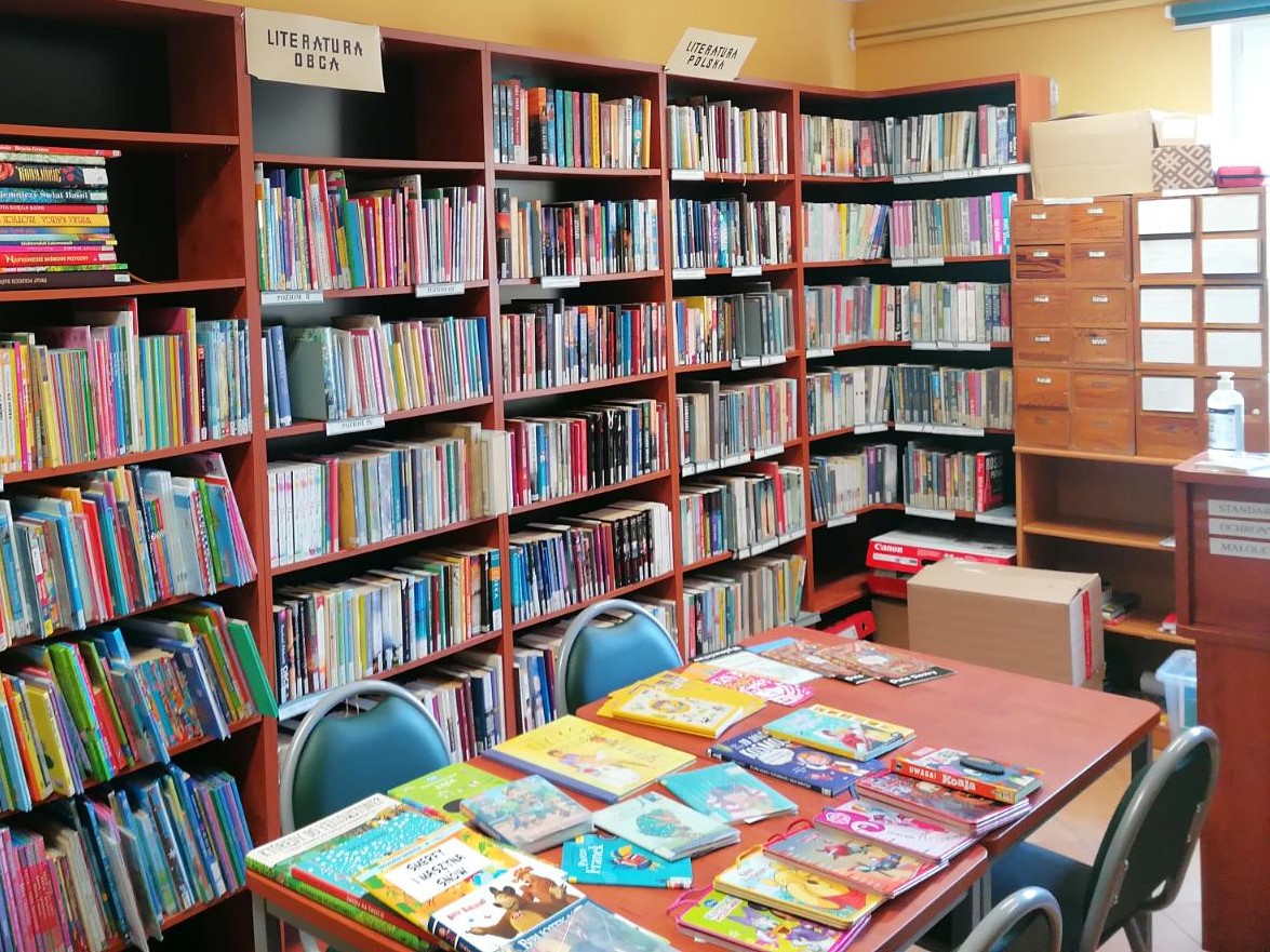 Zdjęcie przedstawiające regały z książkami i stolik dla czytelników.